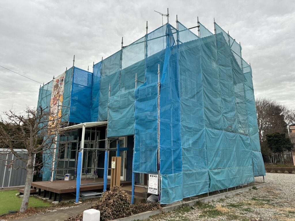 足場組立<br />
（塗料が飛散しないようにメッシュシートもしっかりと貼りました。）