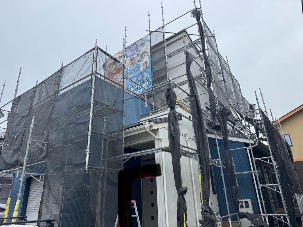 足場組立<br />
（塗料が飛散しないようにメッシュシートもしっかりと貼りました。）